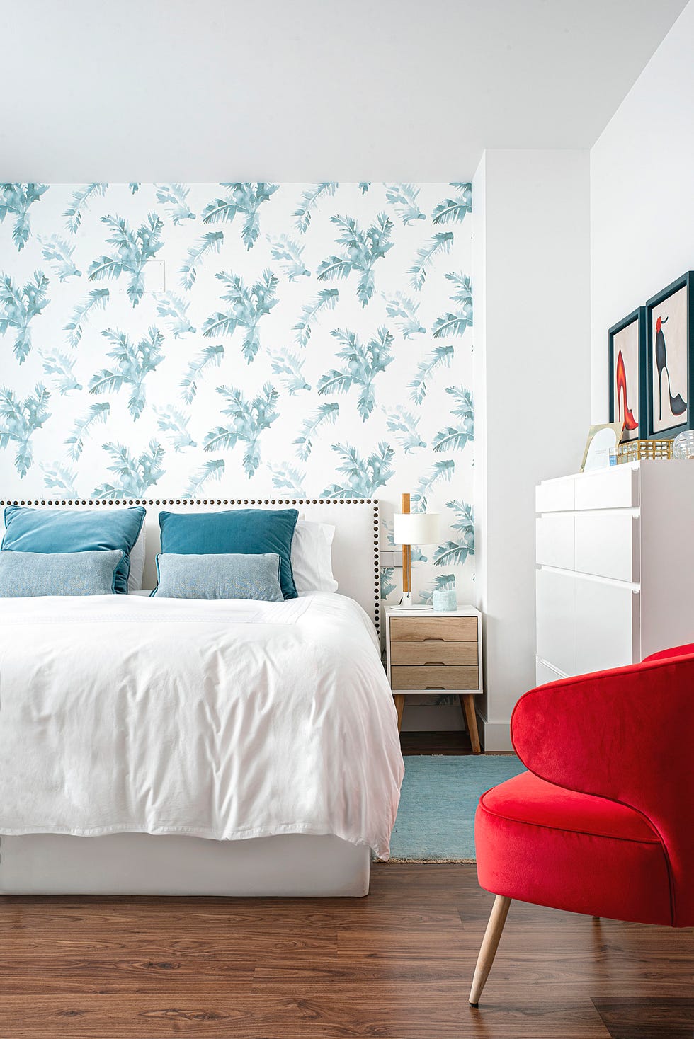 dormitorio con cabecero blanco decorado con remaches y papel pintado con hojas azules