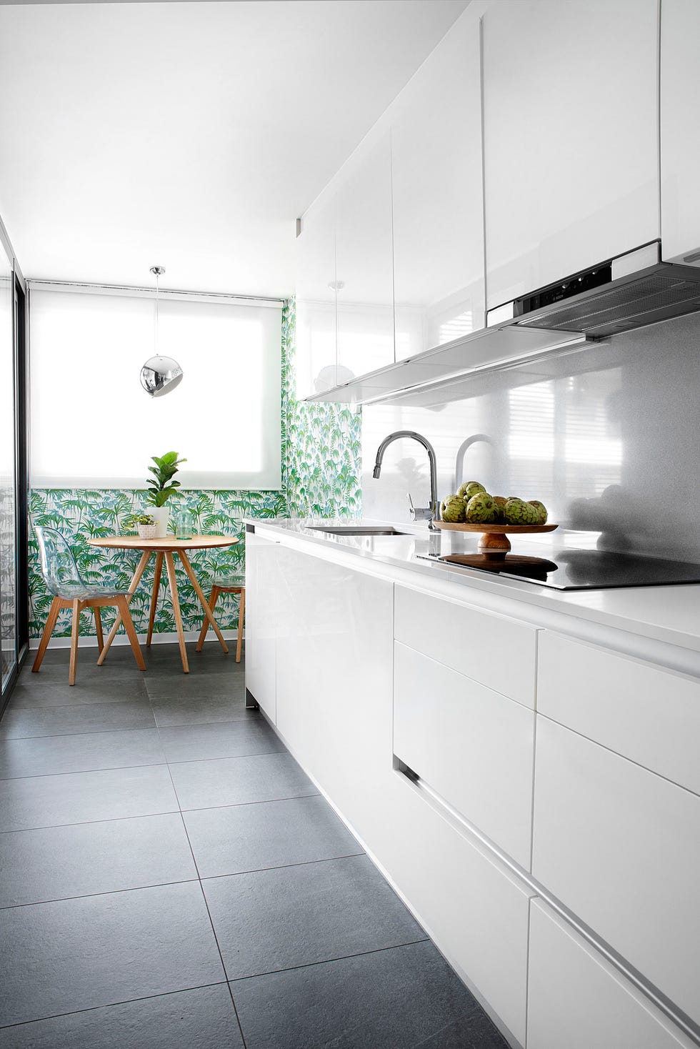 cocina moderna con armarios lacados blancos sin tiradores y office decorado con papel pintado exótico