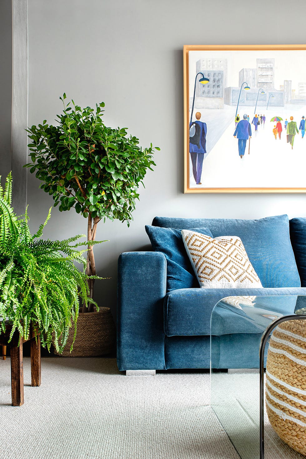 salón con sofá azul, helecho y árbol de interior