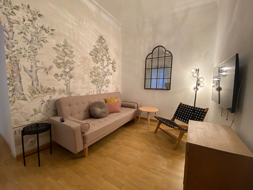 salón con mural inspirado en un bosque, muebles mid century y espejo con cuarterones