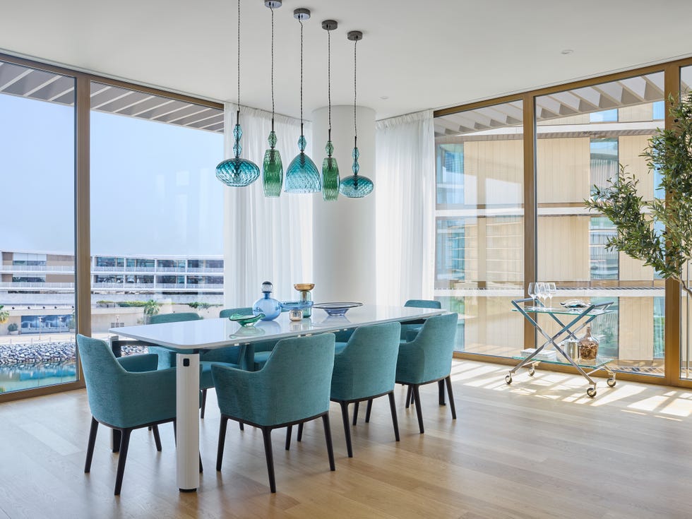 mesa de comedor con sillas azules a juego con las lámparas suspendidas