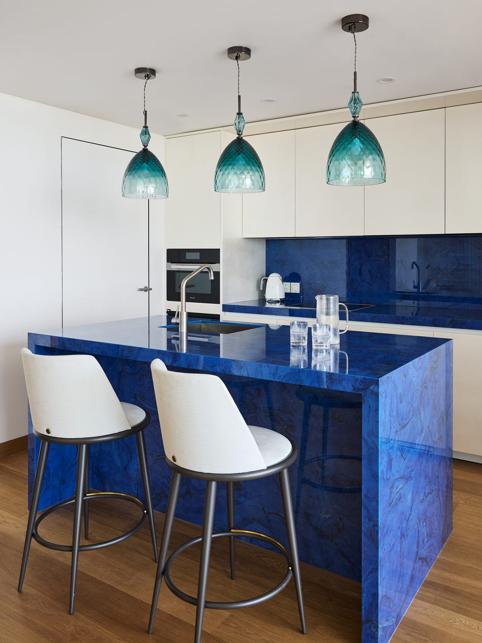 cocina abierta con armarios blancos e isla central azul índigo