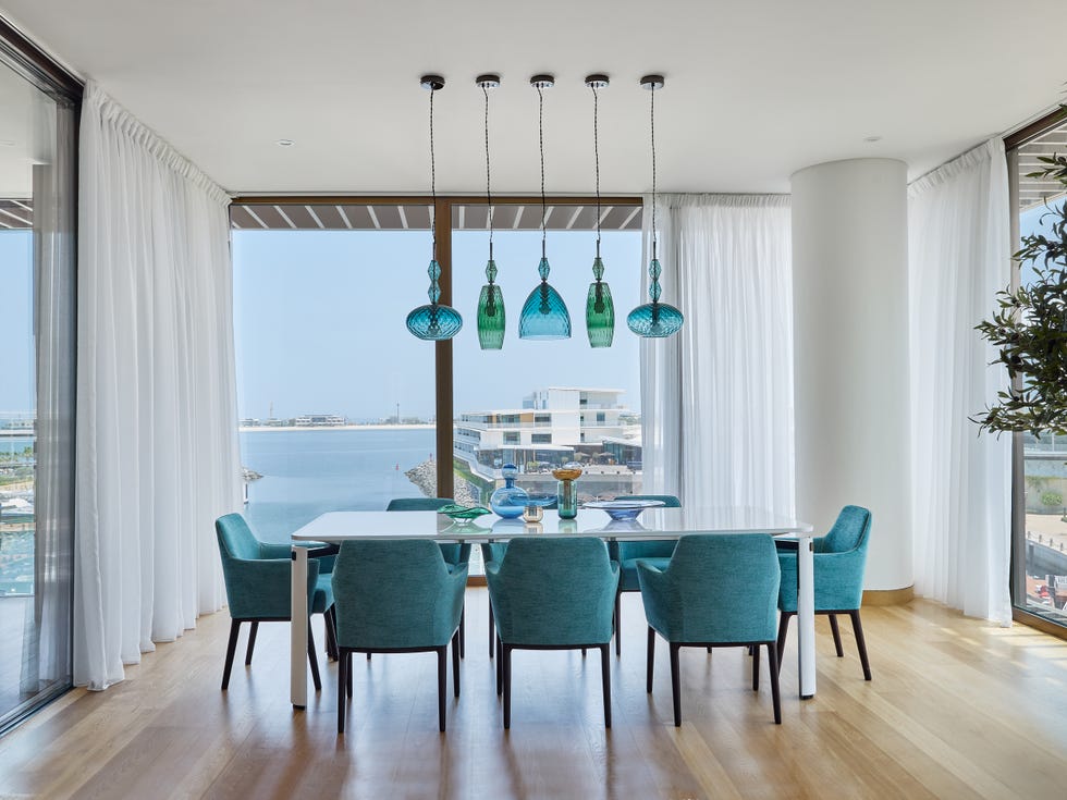 mesa de comedor con sillas azules a juego con las lámparas de cristal azul