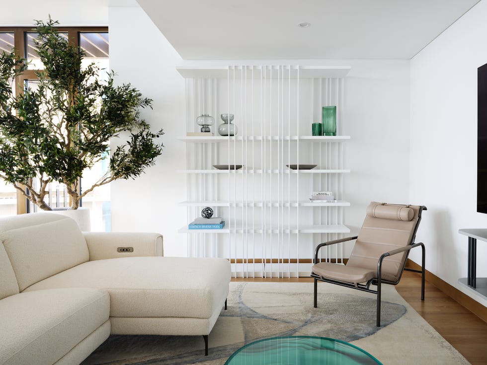 sofá blanco con chaiselongue, butaca y estantería de metal blanco