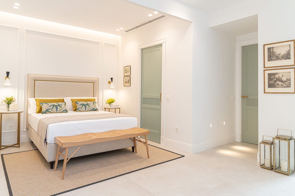 cama con cabecero tapizado en beige y pared con molduras