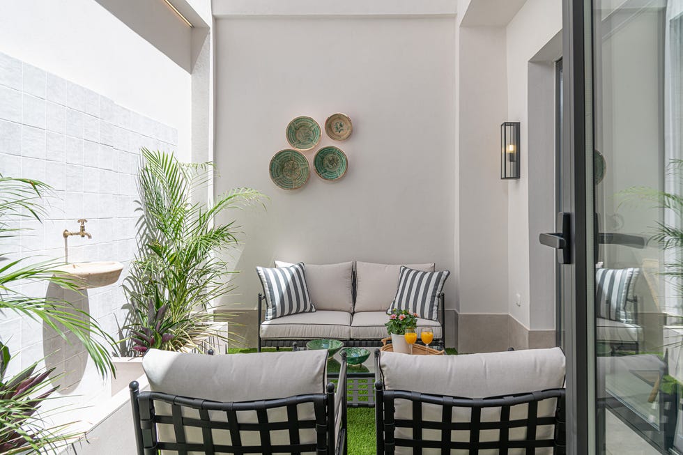 patio interior con sillones, sofá y fuente en la pared
