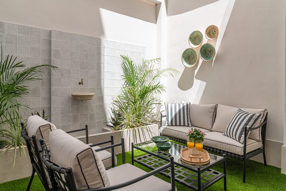 patio interior con sillones, sofá y fuente en la pared