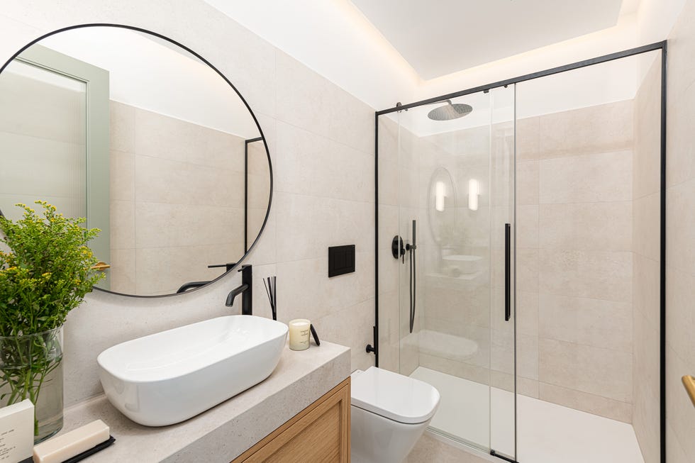 baño con ducha con perfilería negra y espejo redondo