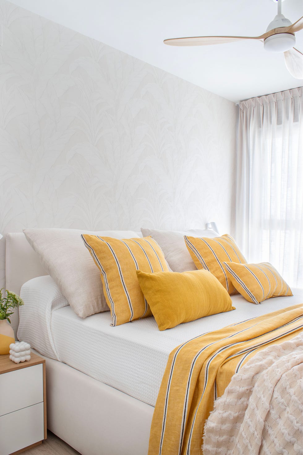 dormitorio con cama tapizada en beige y cojines mostaza