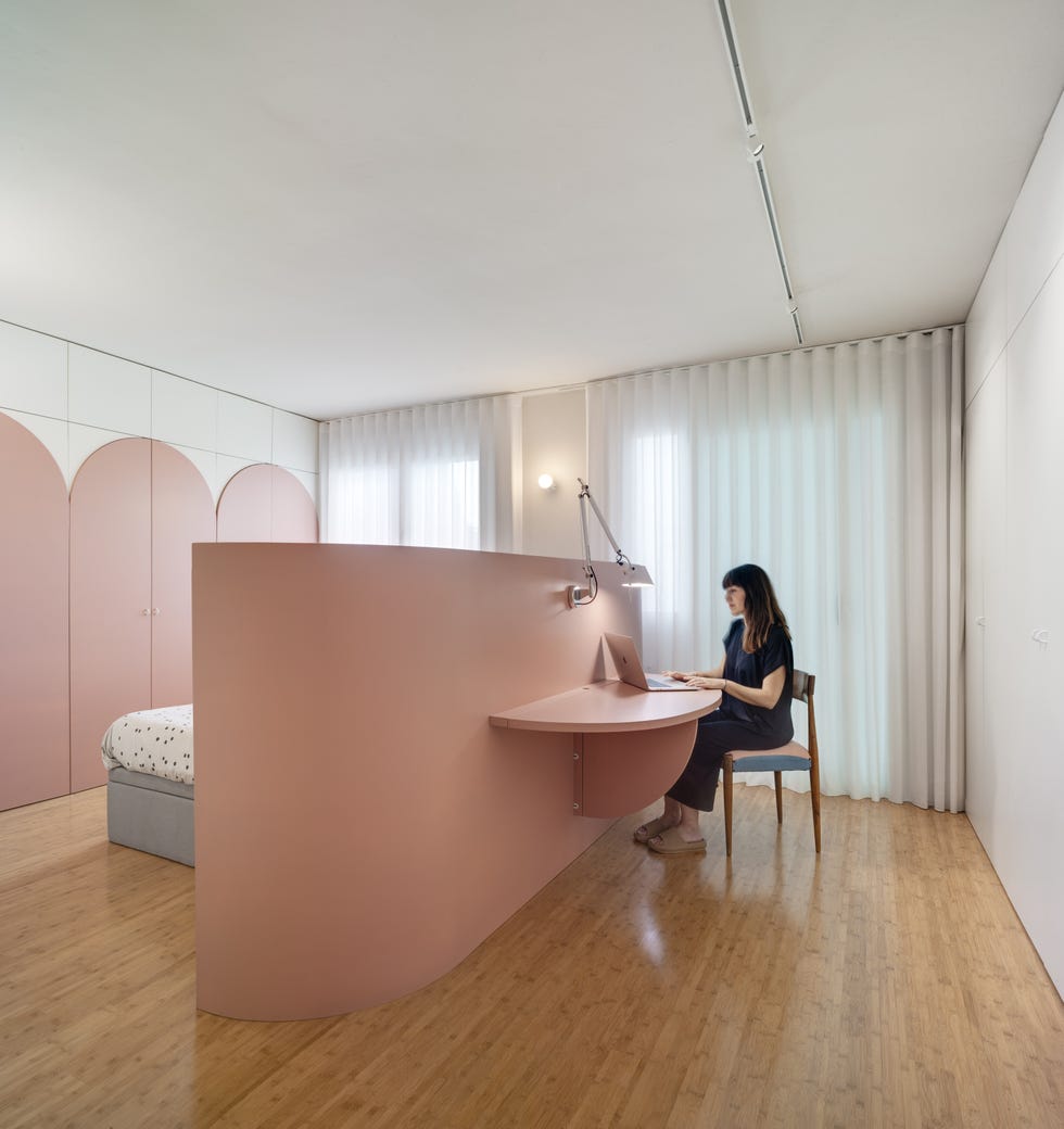 dormitorio moderno de color rosa con escritorio en la parte trasera del cabecero