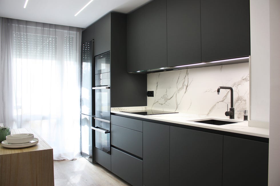 cocina moderna con puertas negras con acabado mate y frente de mármol