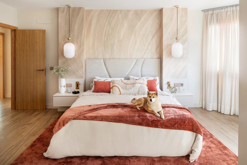 cama con cabecero acolchado gris y lámparas suspendidas