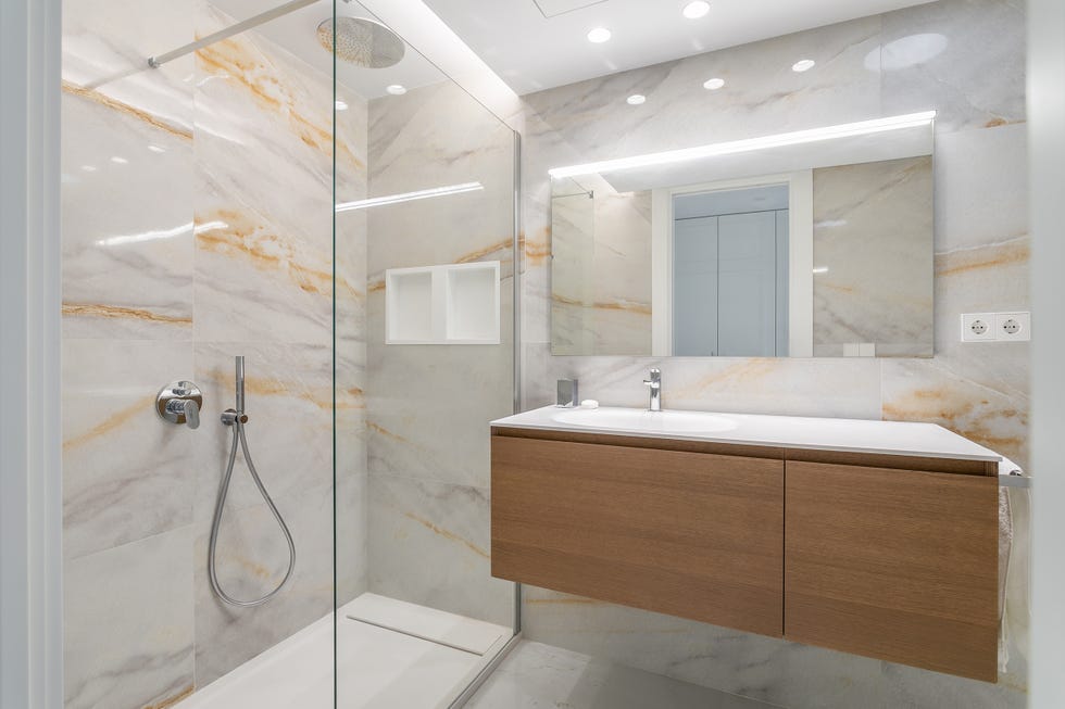 baño con mueble volado de madera y revestimientos de mármol