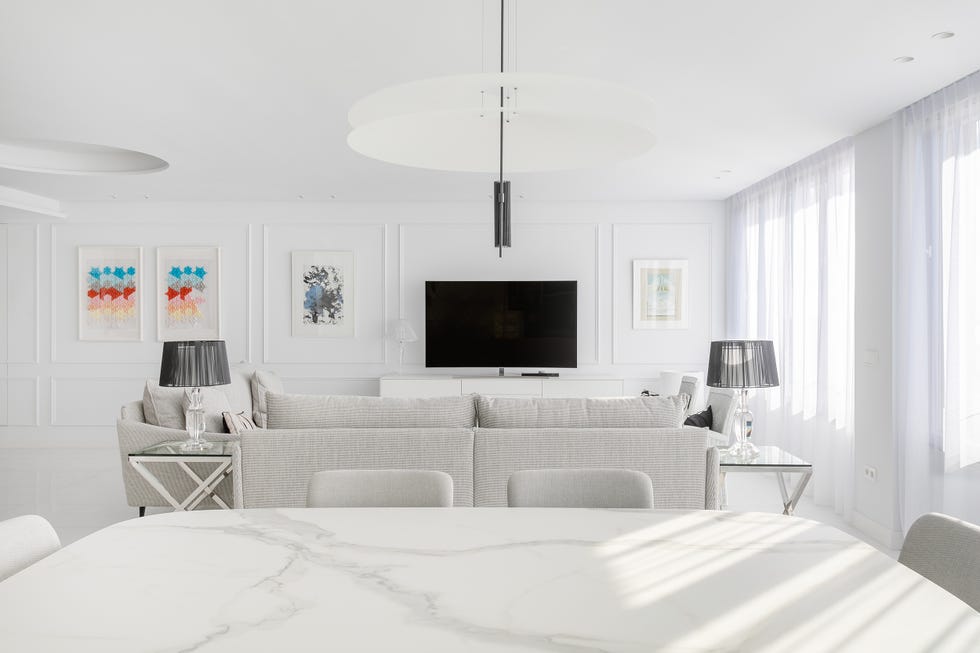 salón comedor con muebles en tonos blancos y paredes con molduras