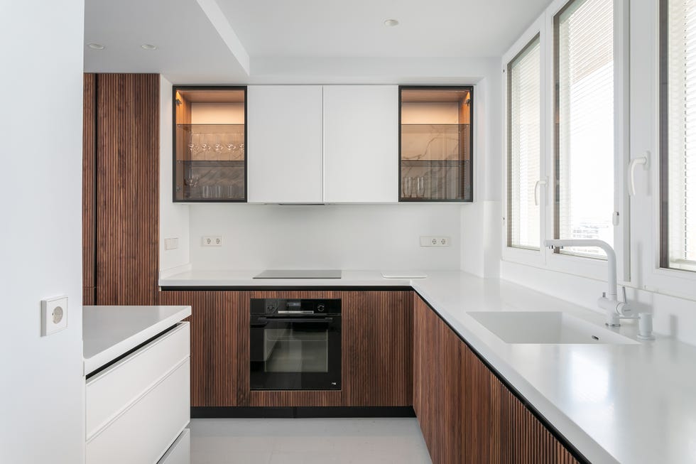 cocina con armarios de madera panelada y encimera blanca