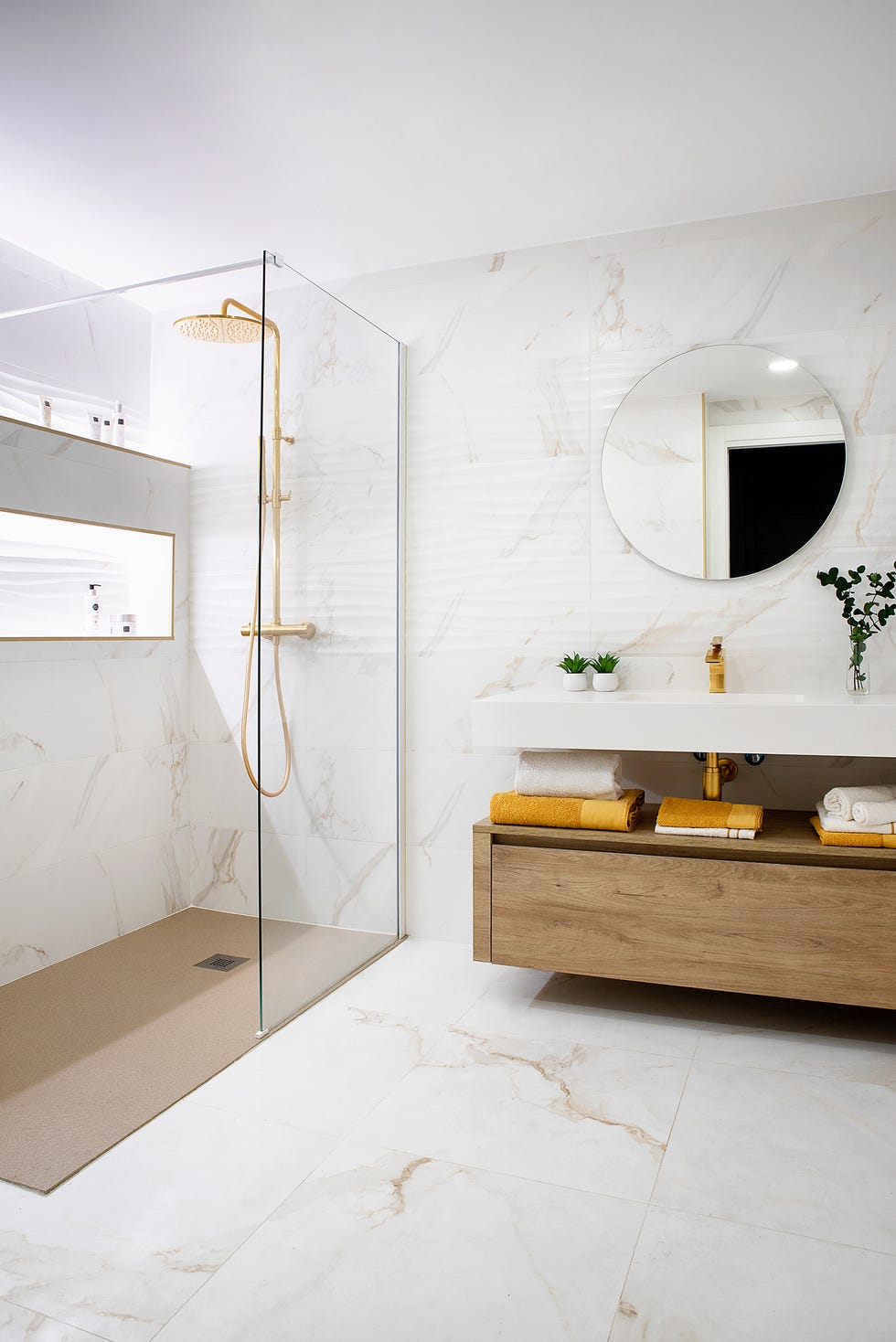 baño moderno con ducha a ras de suelo, revestimiento de mármol y mueble de madera bajolavabo