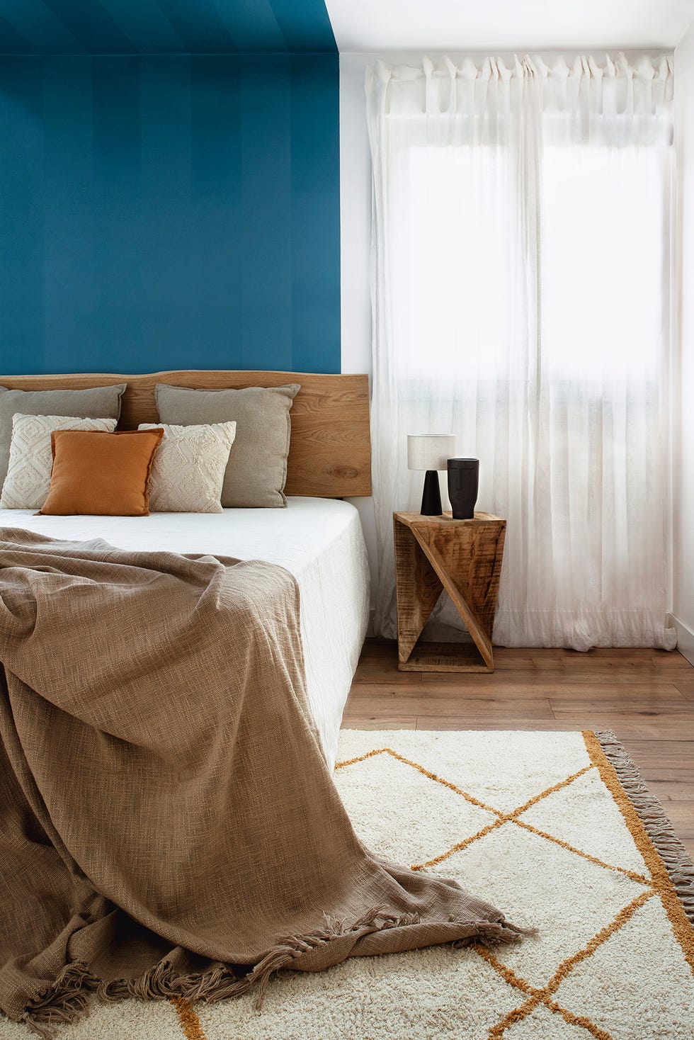 dormitorio moderno con cabecero y mesita de madera y alfombra kilim
