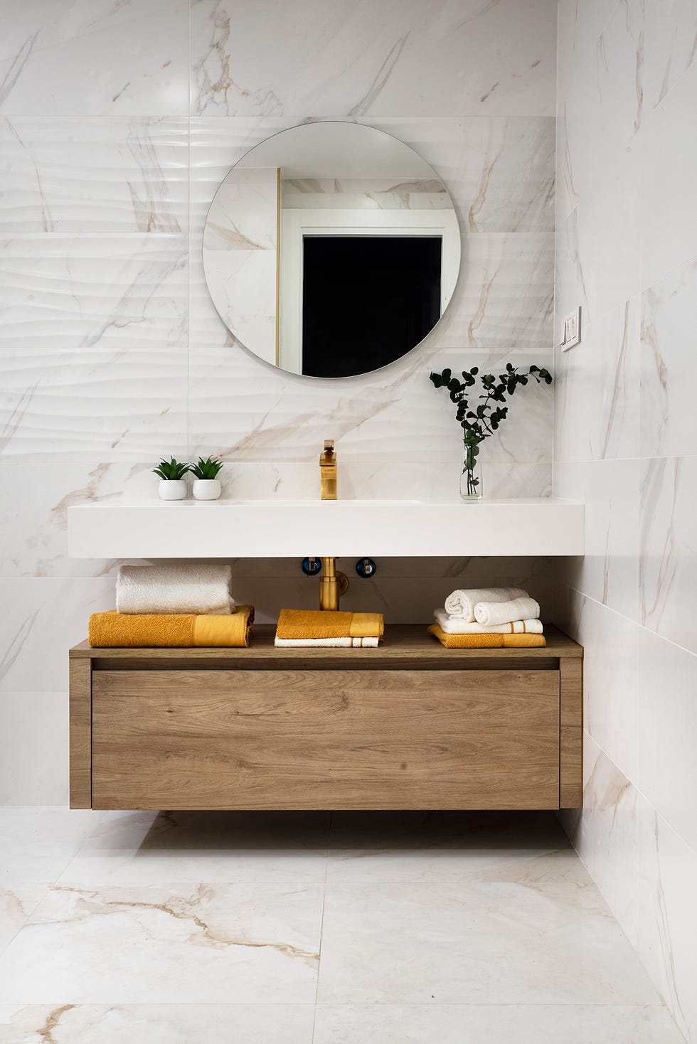 baño moderno con revestimiento de mármol y mueble de madera bajolavabo