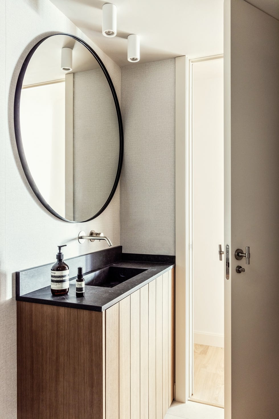 piso de disemueble de baño de madera con encimera de mármol negro y espejo redondontilde;o