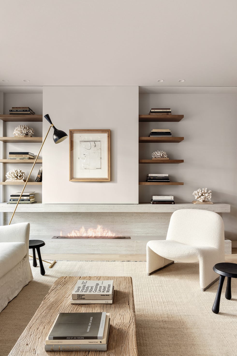 salón con butaca blanca y baldas de madera sobre chimenea de piedra