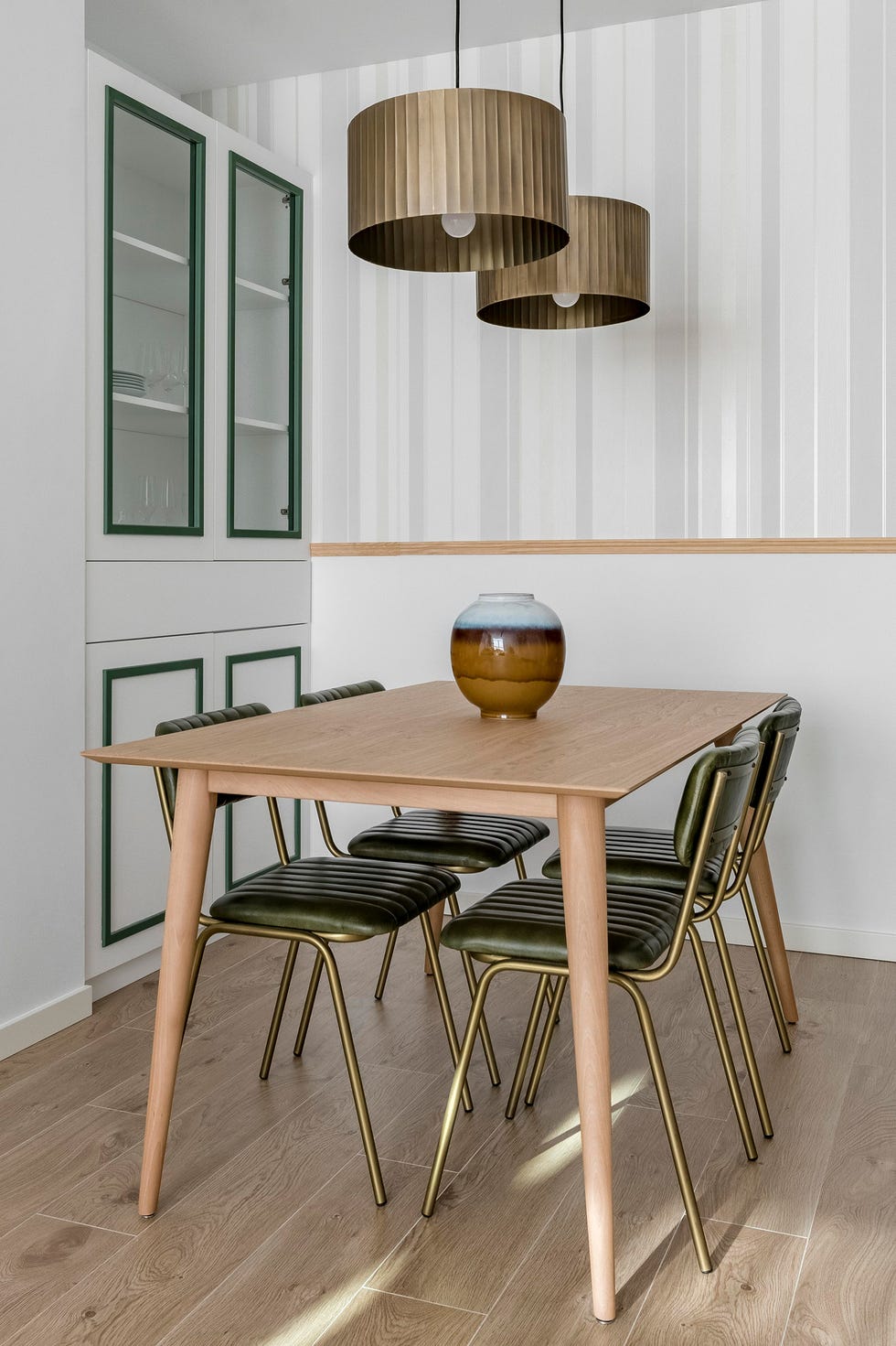 mesa de comedor de madera, sillas de terciopelo verde y vitrina blanca