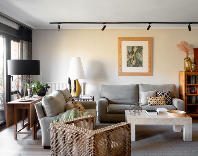 salón moderno con sofás grises, butaca de ratán y mesa de centro de mármol
