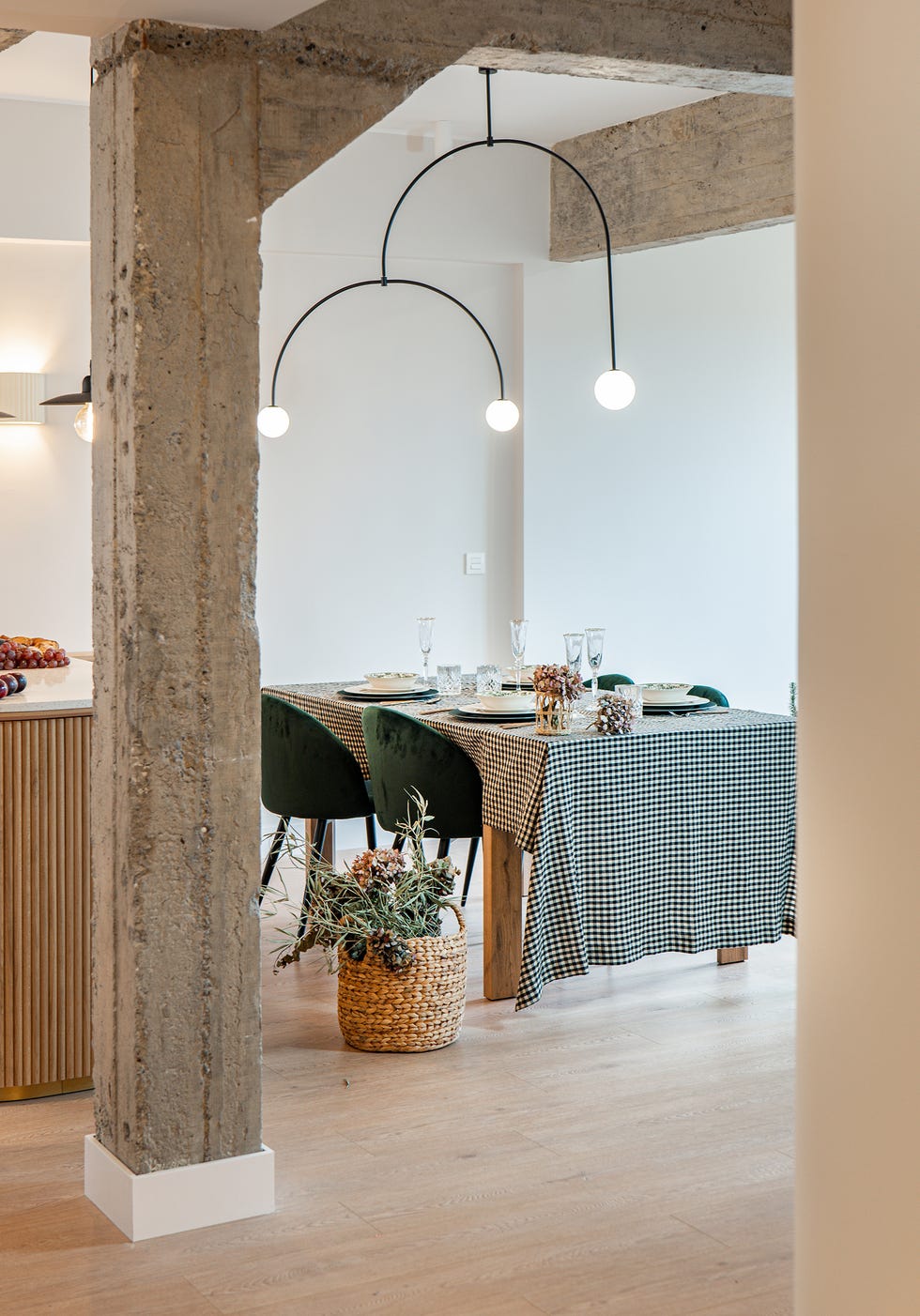 mesa de comedor con sillas de terciopelo verde y columna de hormigón