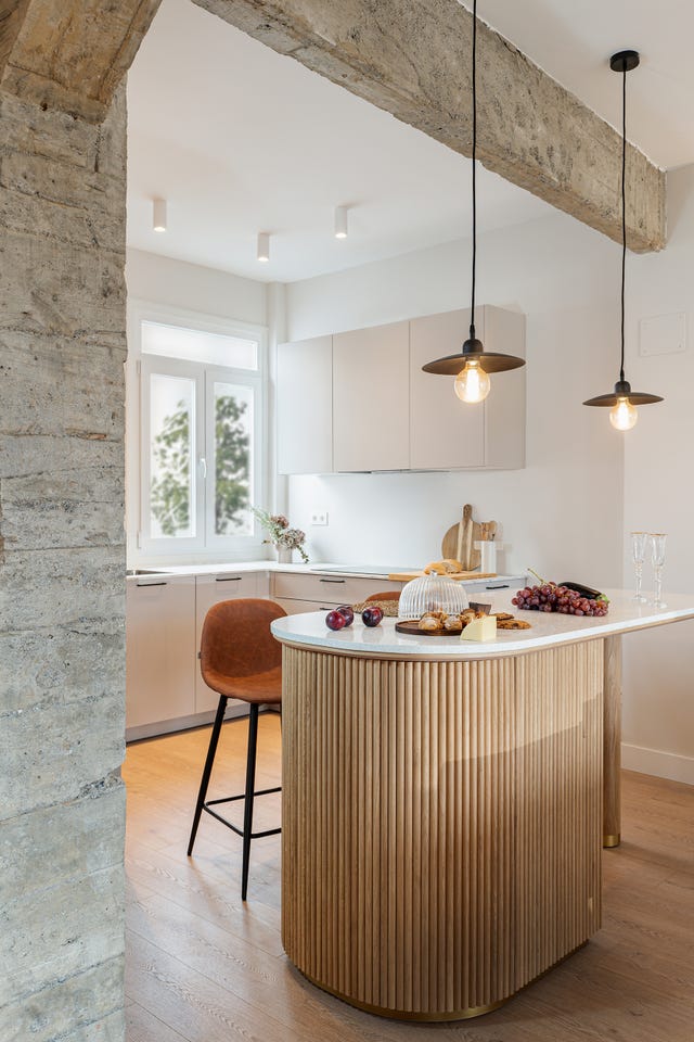 cocina abierta con isla realizada en madera con encimera de mármol