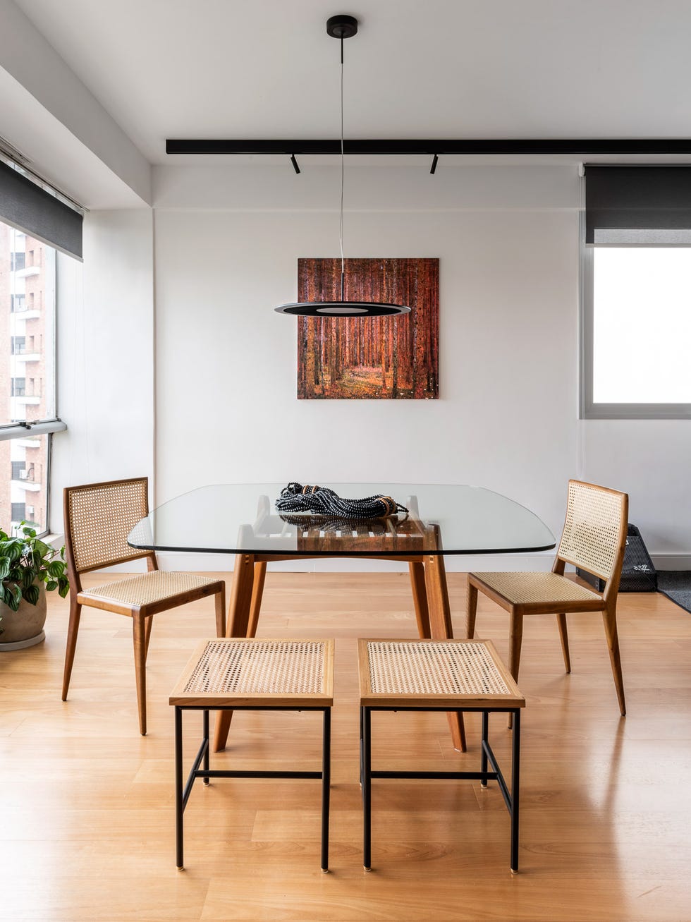 mesa de comedor moderna con sobre de cristal y patas de madera, y sillas de madera y rejilla