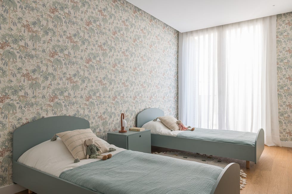habitación infantil con dos camas verdes y papel pintado con dibujos