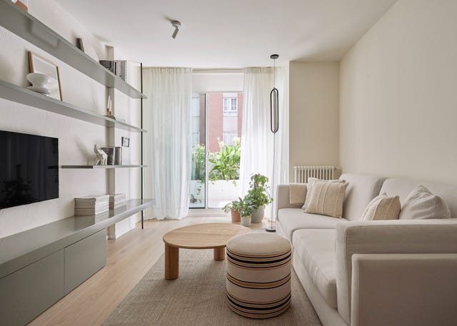 salón con sofá blanco, mesa de centro de madera y puf
