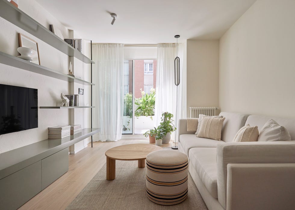 salón con sofá blanco, mesa de centro de madera y puf