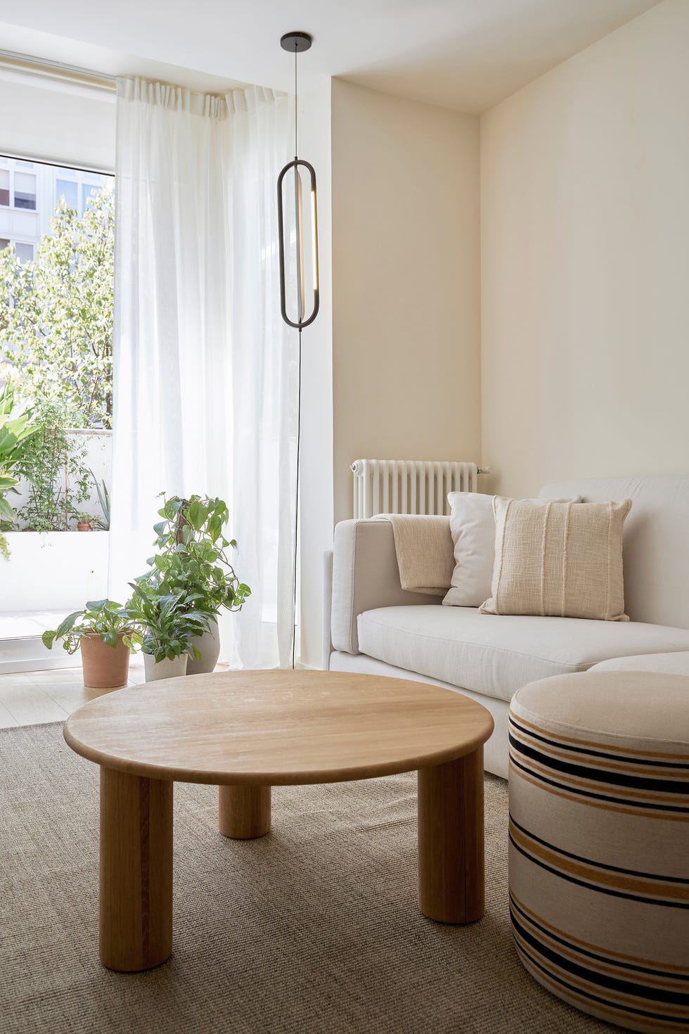 salón con sofá blanco, mesa de centro de madera y puf