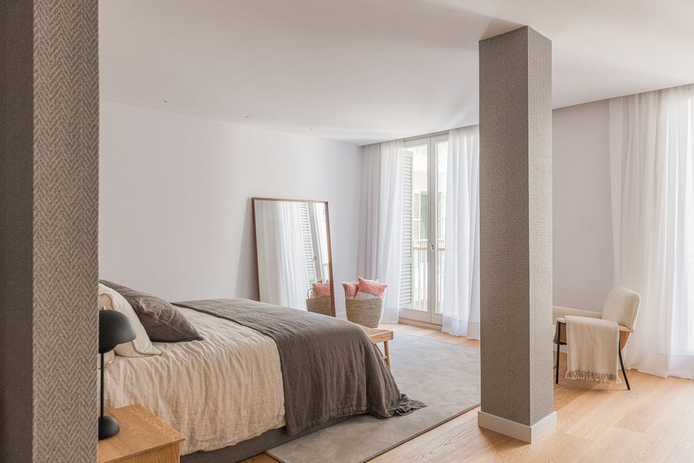 dormitorio suite con butaca y espejo de pie junto a la cama