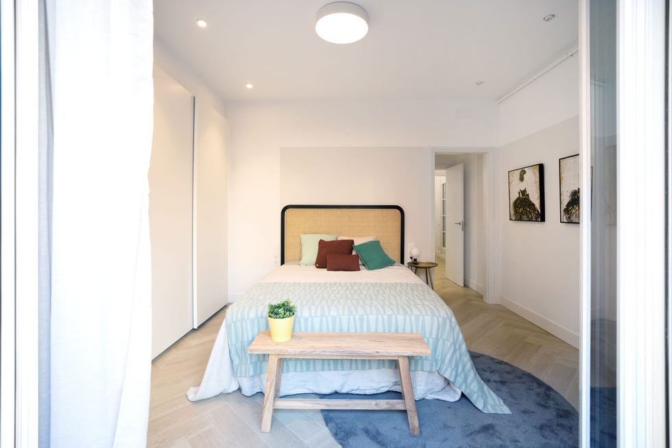 dormitorio nórdico y boho con banco de madera a los pies de la cama