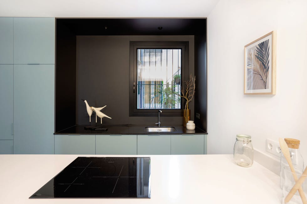 cocina moderna con isla, pared en negro y armarios azules
