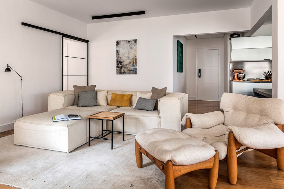 salón de diseño moderno con sofá con chaise longue beige y butaca con reposapiés de madera con cojines beige