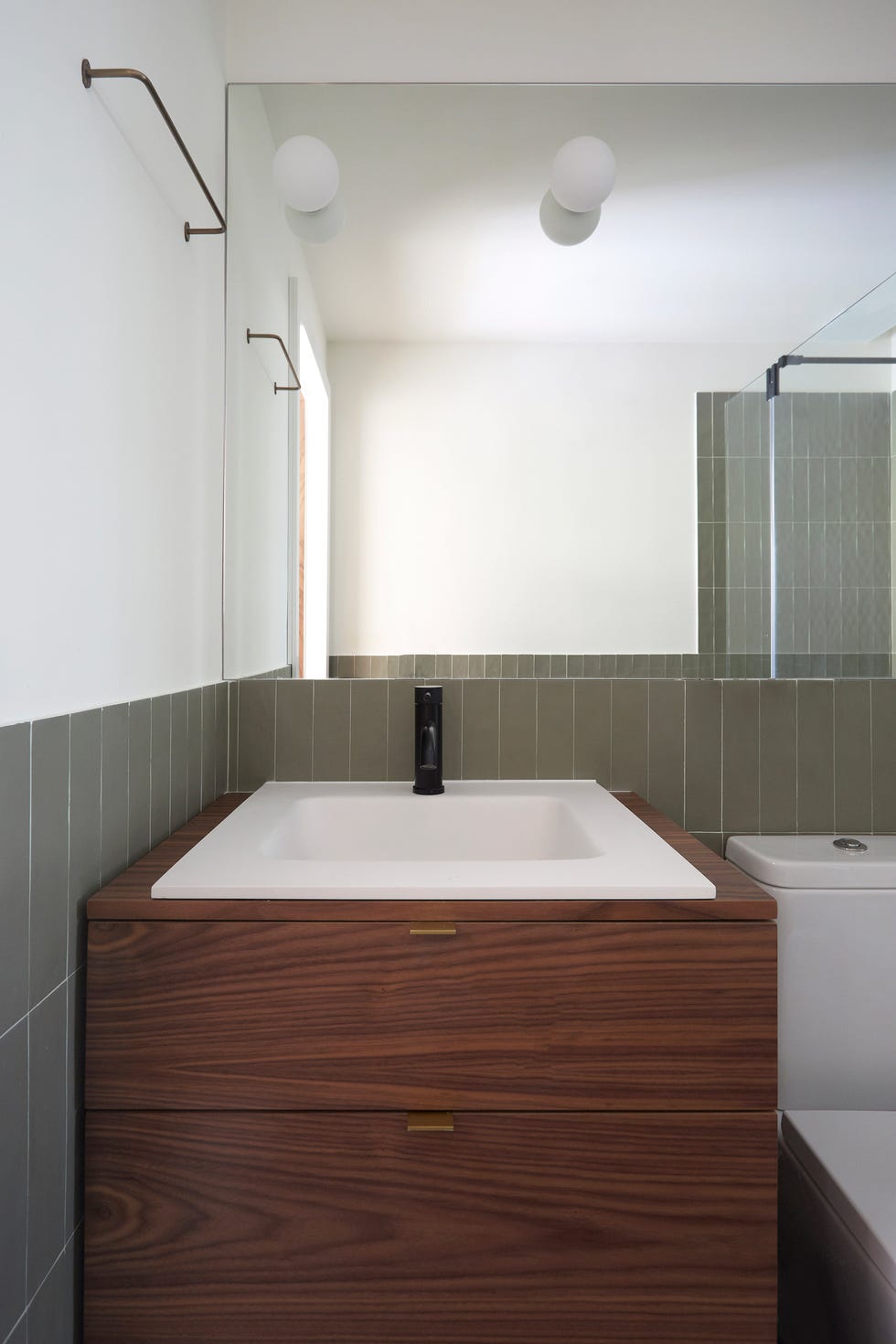 baño con mueble volado de madera y azulejos en verde empolvado