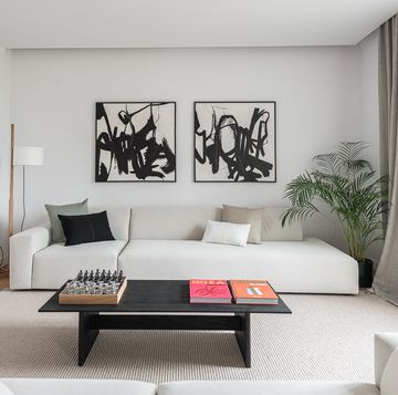 sofás blancos, mesa de centro negra y dos cuadros abstractos