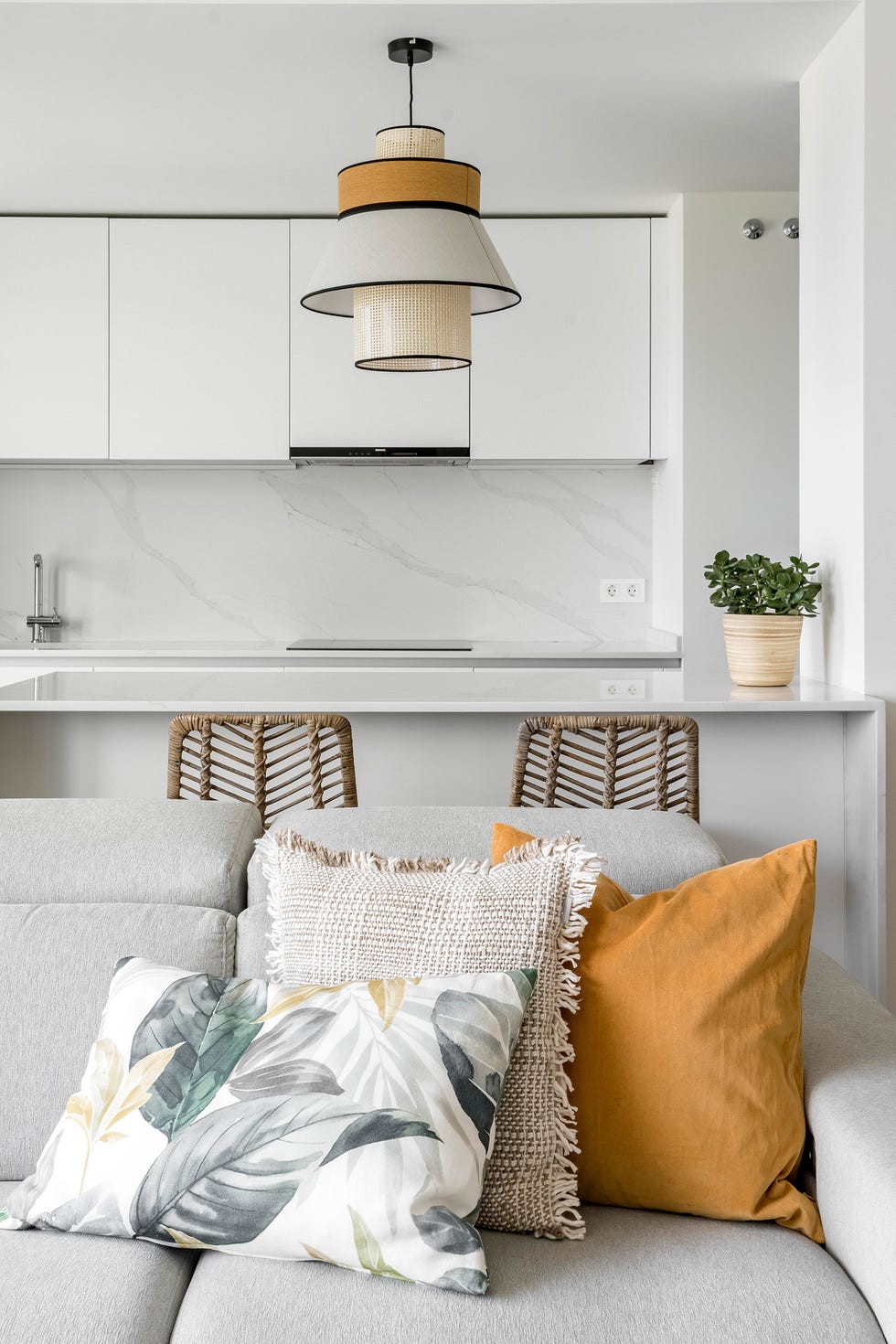cocina blanca de diseño abierto con isla y cojines en el sofá