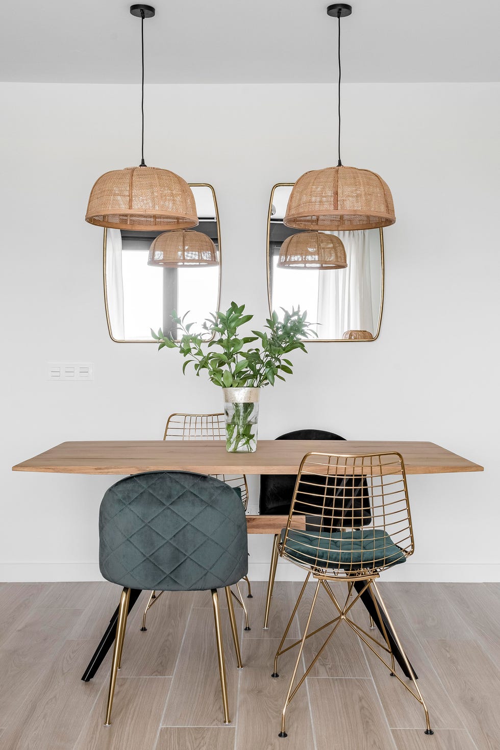 mesa de comedor de madera y acero, sillas de terciopelo verde y lámparas de fibras