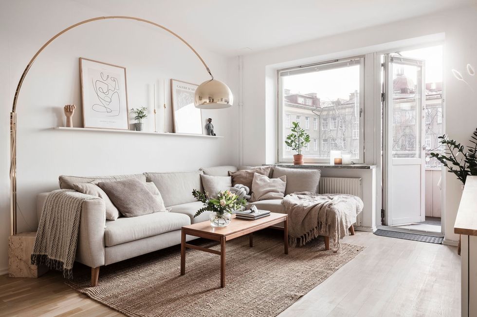 salón de diseño nórdico con sofá con chaise longue gris y lámpara de pie dorada
