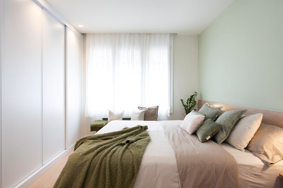 dormitorio con cabecero de madera y pared verde