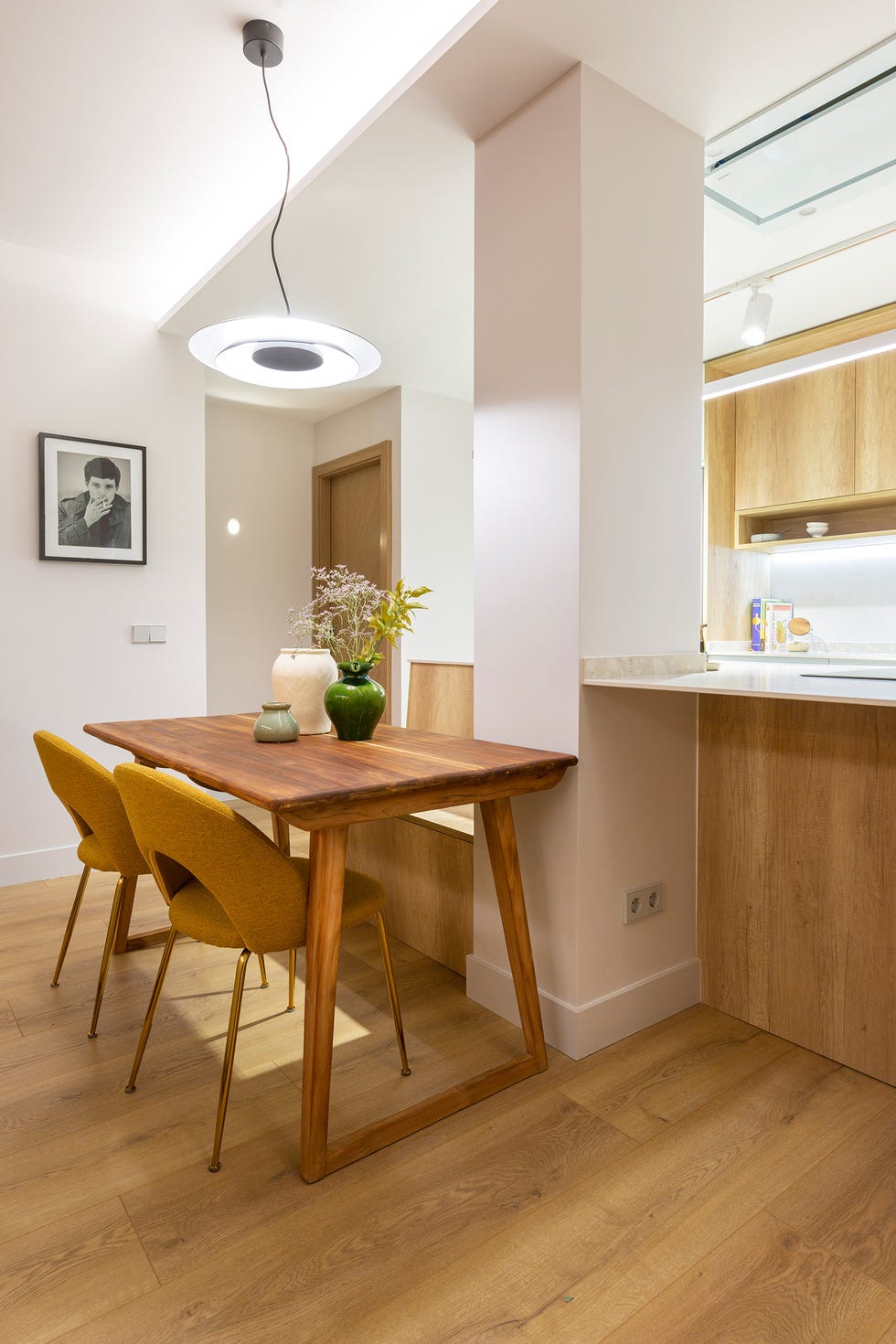 cocina con isla y mesa de comedor de madera con sillas mostaza