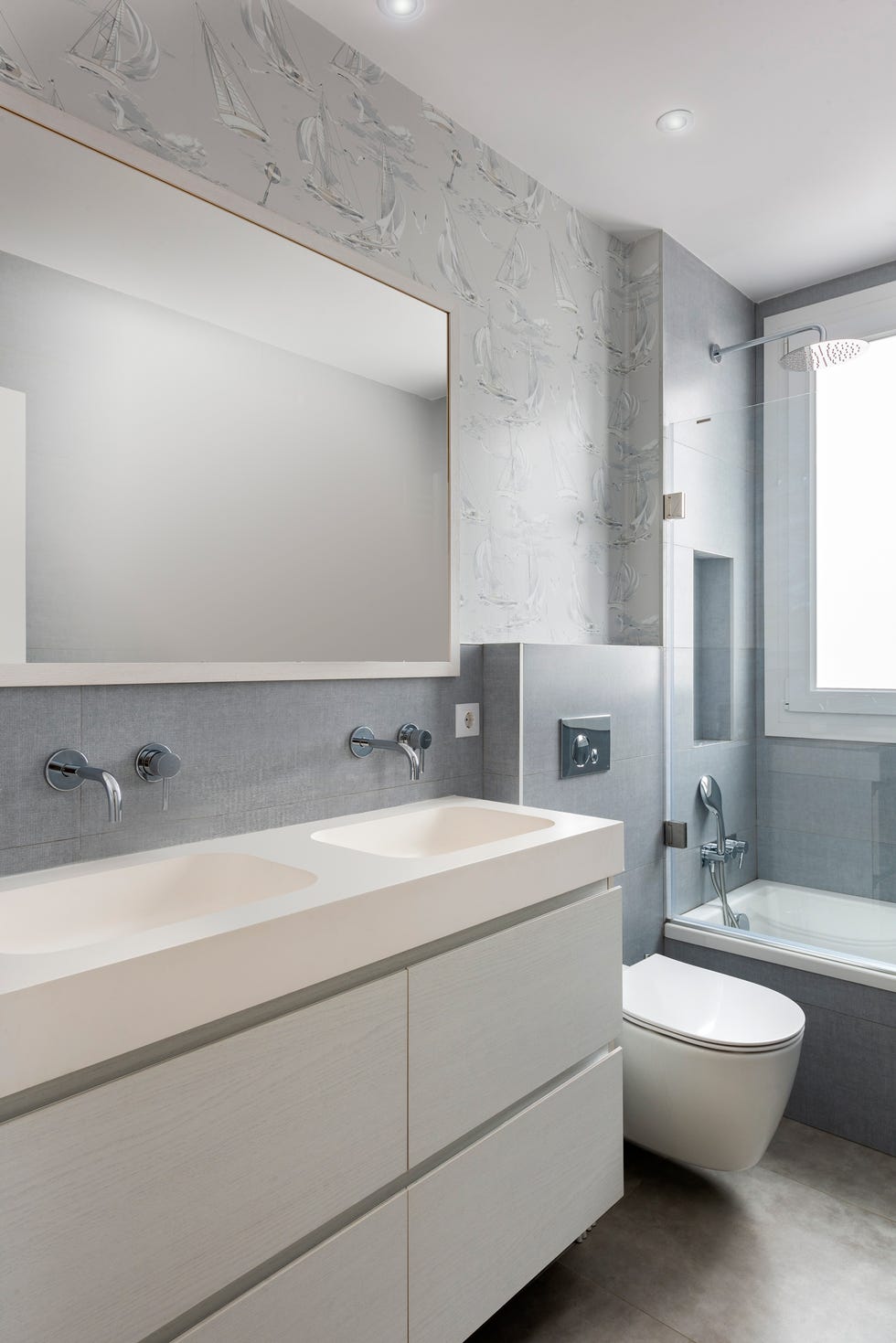 baño moderno con mueble suspendido y papel pintado de barcos