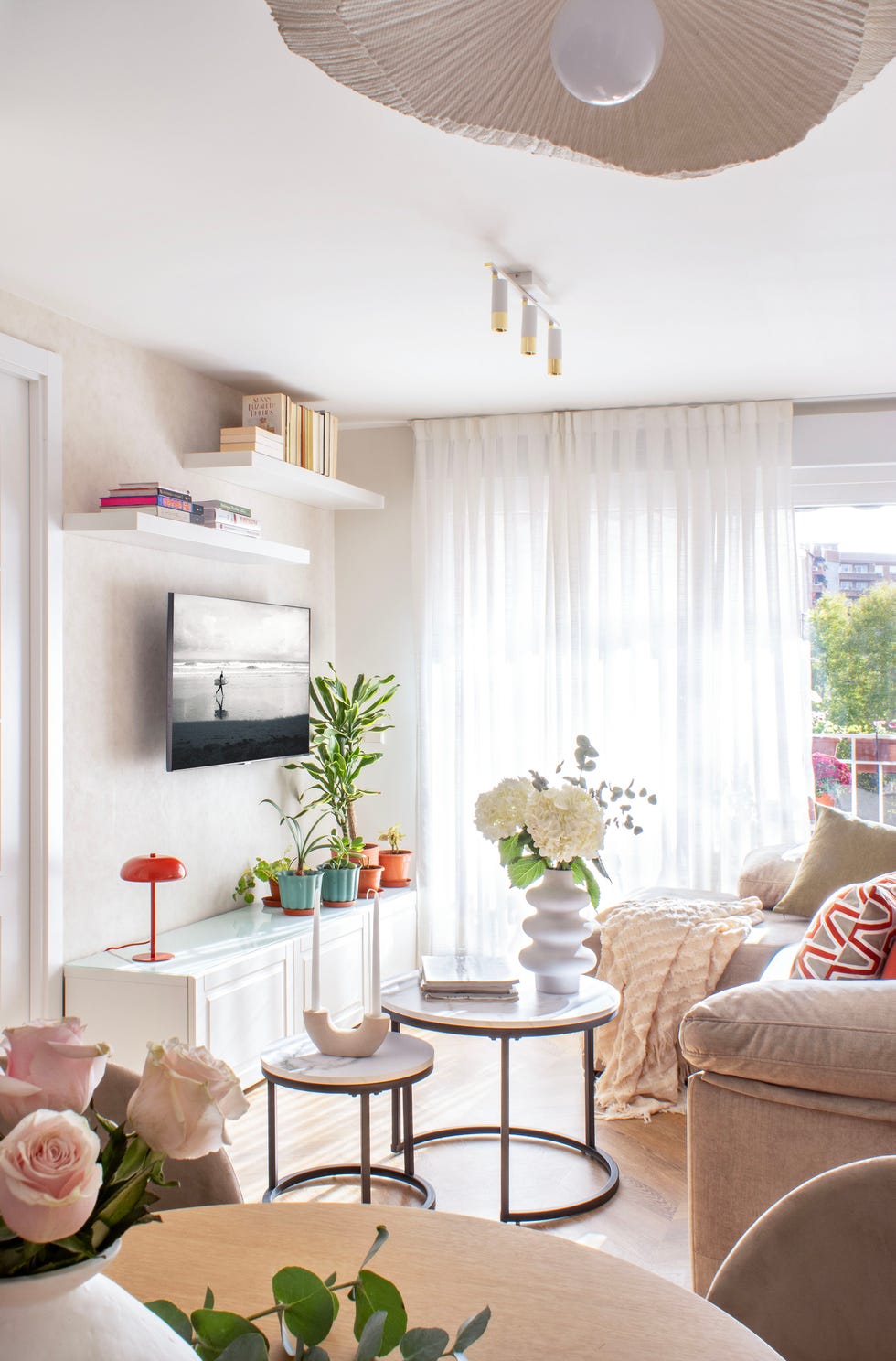 salón con sofá beige, mesas redondas de centro y mueble blanco de tv