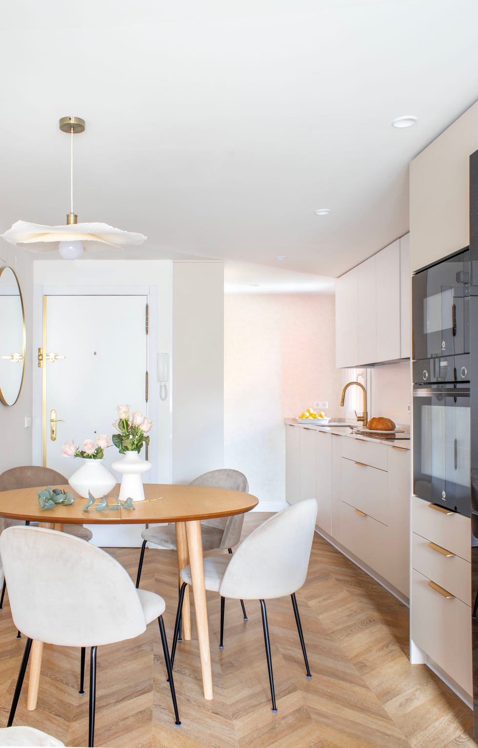 cocina blanca y comedor con mesa redonda de madera y sillas de terciopelo