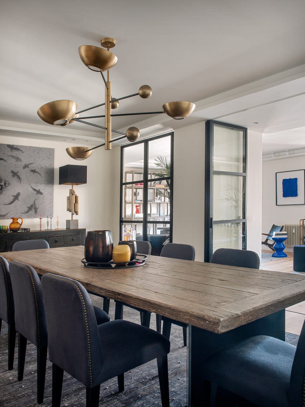 mesa de comedor de madera con sillas tapizadas en azul y lámpara dorada suspendida