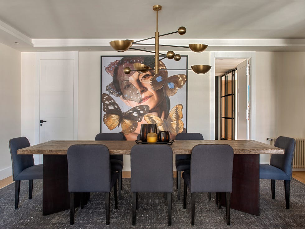 mesa de comedor de madera con sillas tapizadas en azul y lámpara dorada suspendida