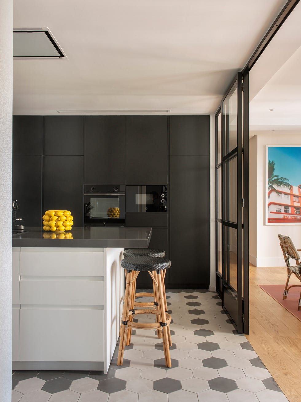 cocina con armarios negros e isla central blanca
